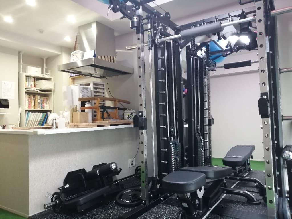 パーソナルジム心身健康道場のトレーニング空間。マルチファンクションラックと受付カウンター上の刀が見える店内